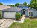 Well-maintained blue single-story home with a two-car garage, neat landscaping, and walkway at 1131 Tyler Lake Cir, Orlando, FL 32839