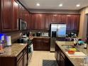Spacious kitchen with granite countertops, stainless steel appliances, and dark wood cabinetry at 13252 Vennetta Way, Windermere, FL 34786