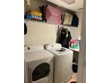 A tidy laundry room area featuring a washer, a dryer, and storage shelves at 13252 Vennetta Way, Windermere, FL 34786