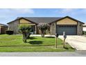 Home exterior with well-maintained lawn, mature bushes, and attached two-car garage at 22 Bradford Ct, Kissimmee, FL 34758