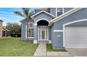 Close up of charming two-story home with a manicured lawn, arched entry and a two car garage at 2556 Volta Cir, Kissimmee, FL 34746