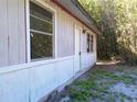 Side view of the home featuring two windows and a white front door with bamboo in the background at 31429 Anna St, Deland, FL 32720