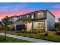 Two-story home boasting a two-car garage, pristine landscaping, and a welcoming facade under a multicolored sky at 4316 Foggy Oak Ln, Sanford, FL 32773