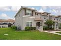 Beautiful townhome exterior featuring lush green lawn, landscaped bushes, and a view of neighboring homes at 4974 Windermere Ave, Kissimmee, FL 34746