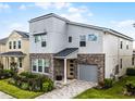 Contemporary two-story home with stone accents, gray siding, well-maintained landscaping, and an attached one-car garage at 8913 Coconut Breeze Dr, Kissimmee, FL 34747