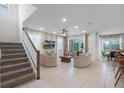Open-concept living room featuring tile floors, modern furniture, a ceiling fan, and sliding glass doors to the patio at 8913 Coconut Breeze Dr, Kissimmee, FL 34747