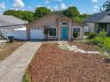 Inviting single-story home with a mulch yard and teal front door, complete with an attached garage at 1115 Naples Dr, Orlando, FL 32804