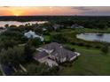 Picturesque aerial view of a home with mature trees and a serene lake at sunset at 13025 Lake Roper Ct, Windermere, FL 34786