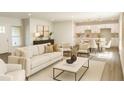 An open concept living room, kitchen and dining area are decorated in neutral colors and modern furnishings at 1304 Hillsborough Ct, Kissimmee, FL 34759