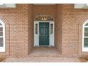 Close up of a front door with white sidelights and transom window, surrounded by a brick facade at 1908 S Farm Rd, Deland, FL 32720