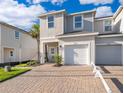 Two-story townhouse showcasing one car garage, neutral colors, palm tree, and a brick driveway at 2596 Penguin Blvd, Davenport, FL 33837