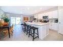 Open kitchen featuring white cabinets, a large island with bar seating, and stainless steel appliances at 2596 Penguin Blvd, Davenport, FL 33837