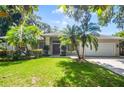 Inviting home with a green lawn, palm trees, and a two-car garage, offering a blend of comfort and style at 2905 Elbert Way, Kissimmee, FL 34758