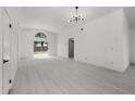 Bright living room with light wood-look flooring, modern light fixture, and large arched window at 2978 Stillwater Dr, Kissimmee, FL 34743