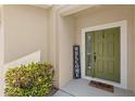 Welcoming entrance with an olive-green door, 'Welcome' sign, and verdant landscaping at 3055 Ashland N Ln, Kissimmee, FL 34741