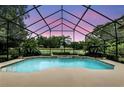 Sparkling pool with screen enclosure, lush landscaping, and view of the property beyond at 518 Stephanie Ct, Lake Mary, FL 32746