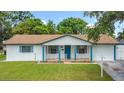 Attractive single-story home boasts a manicured lawn, and inviting front porch with eye-catching blue pillars at 1328 S Oxalis Ave, Orlando, FL 32807