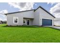 Charming single-Gathering home featuring a blue garage door, lush lawn, and modern architectural details at 16057 Sw 17Th Ave, Ocala, FL 34473