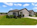 Well-kept home featuring green lawn, tidy landscaping, and a two-car garage under a partly cloudy sky at 311 Eaglecrest Dr, Haines City, FL 33844