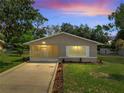 Evening shot of a single-story home with screened porch and manicured lawn and landscaping at 458 Spring Ln, Ocala, FL 34472