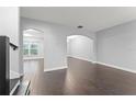 Open-concept living area with hardwood floors, arched doorways, and neutral gray walls at 605 Elbridge Dr, Kissimmee, FL 34758