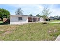 Side view of a single-story home featuring white stucco, brick accents, and a green lawn at 1432 Findlay St, Deltona, FL 32725