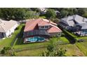 Aerial view of a private screened-in pool and patio with a terracotta tile roof, surrounded by a lush green yard at 1528 Langham Ter, Lake Mary, FL 32746