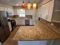Modern kitchen with white cabinets, granite countertops, stainless steel appliances, and stylish pendant lights at 2414 Willow Oak Dr, Edgewater, FL 32141