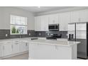 Modern kitchen with white cabinets, stainless steel appliances, and a stylish gray tile backsplash at 353 Belmond Dr, Debary, FL 32713