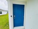 The vibrant blue front door makes a welcoming statement with modern smart lock at 4295 Twisted Twig Bnd, Kissimmee, FL 34746