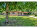 A cozy single-story house with a covered carport and lawn, partially shaded by a mature tree at 102 Mayrose Dr, Sanford, FL 32771