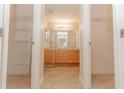 Hallway view of bathroom featuring dual sinks, vanity, and walk-in closets on each side at 1425 Hollyberry Pl, The Villages, FL 32162