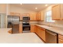 Well-equipped kitchen features stainless appliances, natural wood cabinets, and a breakfast bar at 1425 Hollyberry Pl, The Villages, FL 32162