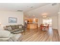 Bright living room with wood flooring, comfortable seating, and open concept to the kitchen and dining area at 1425 Hollyberry Pl, The Villages, FL 32162
