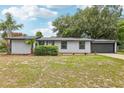 A well-maintained single-story home with a manicured lawn, mature landscaping, and an attached garage at 18015 Beach St, Umatilla, FL 32784