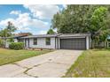 Beautifully renovated house featuring black trimmed windows, a two-car garage, and mature trees at 18015 Beach St, Umatilla, FL 32784