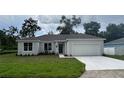 Charming single-story home with a gray roof, a freshly-poured white driveway, and a well-manicured lawn at 1889 15Th St, Orange City, FL 32763