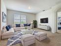 Bright living room with a large window, plush seating, and a modern entertainment center at 313 Sofia Ln, Lake Alfred, FL 33850