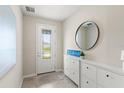 Inviting foyer with tiled flooring, a decorative mirror, a shoe storage cabinet, and a stylish front door at 5065 Sparkling Water Way, Kissimmee, FL 34746