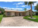 Inviting single-story home featuring a beige exterior, metal roof, and a brick driveway at 708 Duffer Ln, Kissimmee, FL 34759