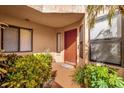 Inviting home entrance with a red front door, lush plants, and natural light at 7421 Sugar Bend Dr # 7421, Orlando, FL 32819