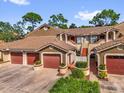 Condo featuring multiple units, red garage doors, and verdant green landscaping at 7421 Sugar Bend Dr # 7421, Orlando, FL 32819