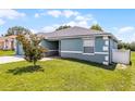 Side view of home showcasing well-maintained lawn, attractive paint color, and brick walkway at 141 Winsor Ave, Davenport, FL 33837