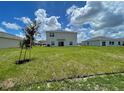 View of the back exterior of the home with large lawn at 228 Aquamarine Ln, Kissimmee, FL 34758