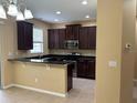Modern kitchen with dark wood cabinets, stainless steel appliances, and a breakfast bar at 5377 Via Appia Way, Sanford, FL 32771