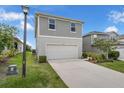 Two-story home featuring gray siding and a white two-car garage, complemented by landscaped yard at 7367 Catania Loop, Clermont, FL 34714