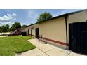 Tan home featuring a tidy side yard with concrete walkway, complemented by dark fencing and landscaped elements at 761 Golden Sunshine Cir, Orlando, FL 32807