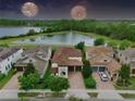 Aerial view of a two-story home near a tranquil lake and lush greenery showcases a serene and picturesque setting at 8752 Lookout Pointe Dr, Windermere, FL 34786