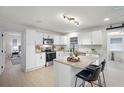 Well-lit kitchen featuring white cabinets, stainless steel appliances, granite countertops and modern island seating at 2932 Carriage Dr, South Daytona, FL 32119