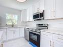Modern kitchen with white cabinets, stainless steel appliances, and quartz countertops at 611 S Montgomery Ave, Deland, FL 32720